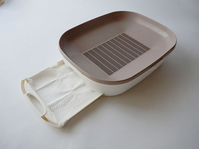 すのこ式トイレの下段にペットシートをセットする様子
